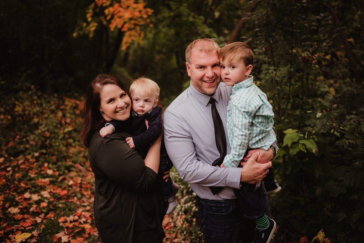 Family enjoying a fall photo session surrounded by colorful autumn foliage.