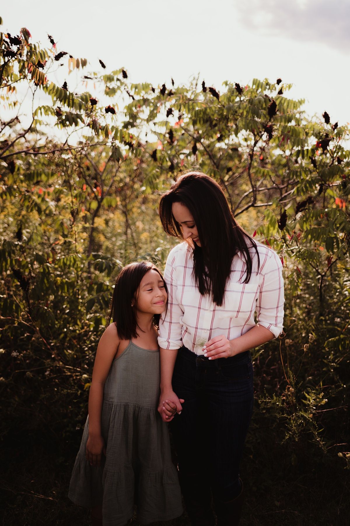 Two people sharing a tender moment among autumn trees at sunset while holding hands.
