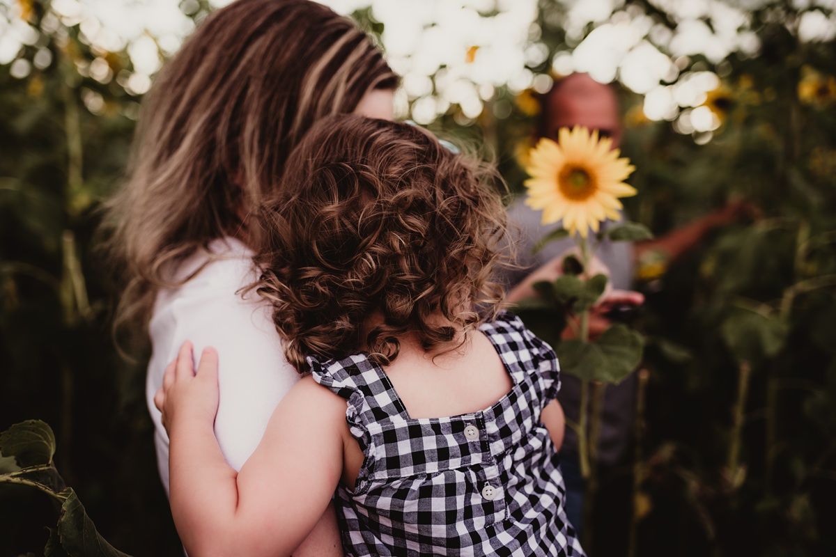 A tender embrace shared between family members in a sunflower field.