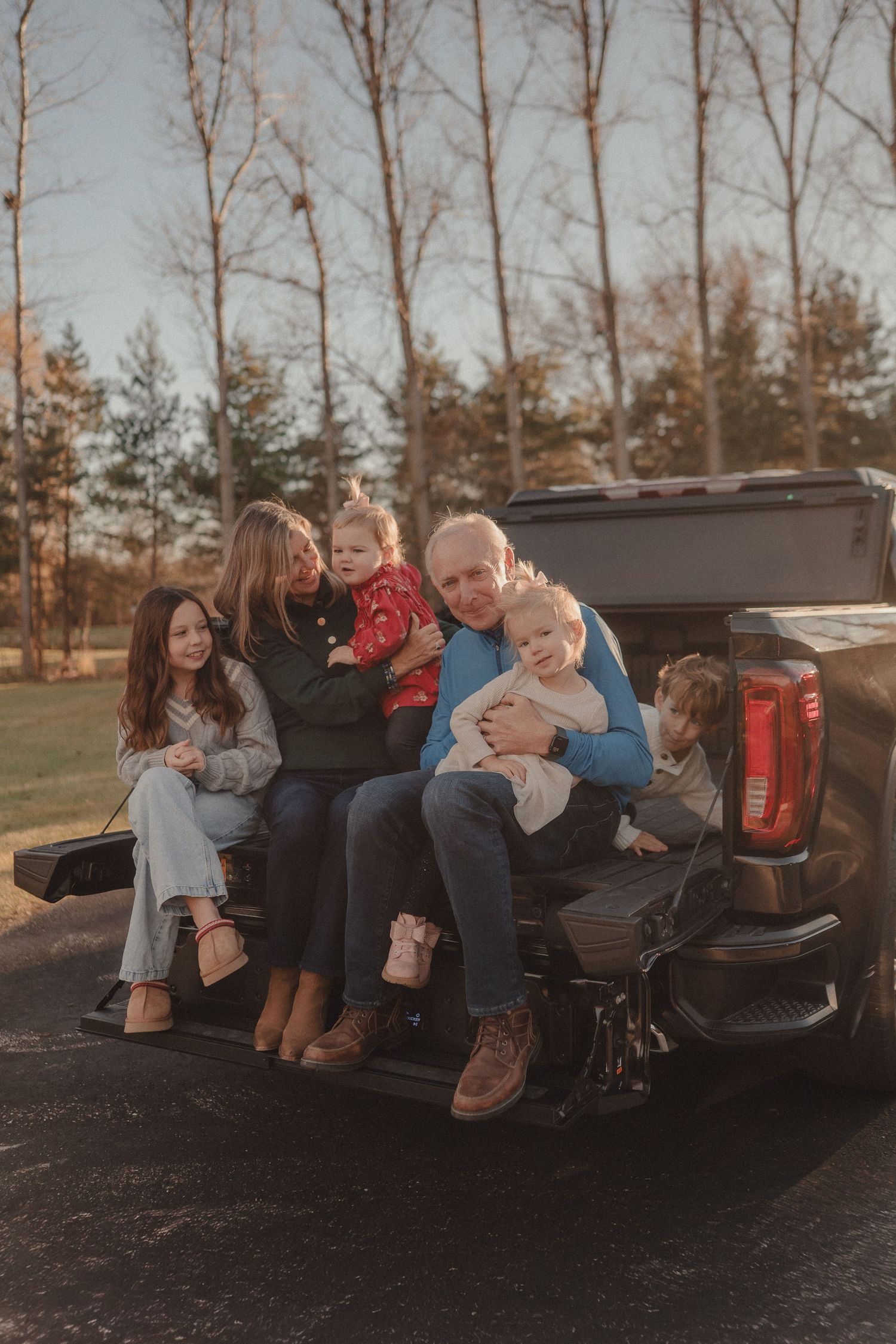 Group relaxing in back of pickup truck during sunset photoshoot.