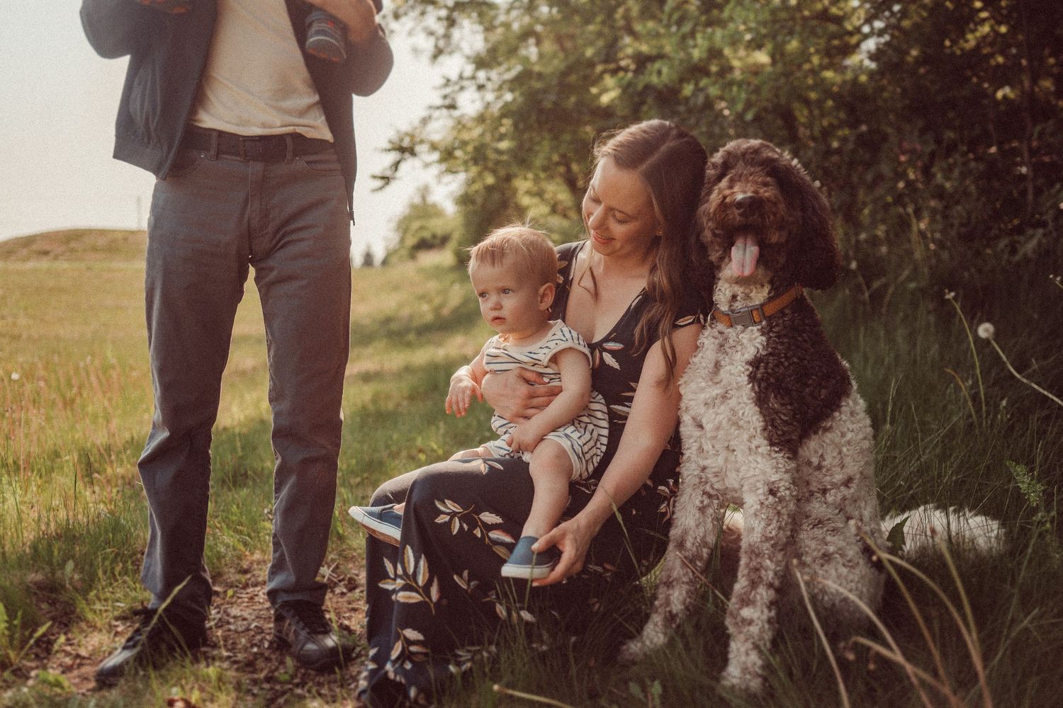 A family relaxing outdoors with their large spotted dog on a nature path.