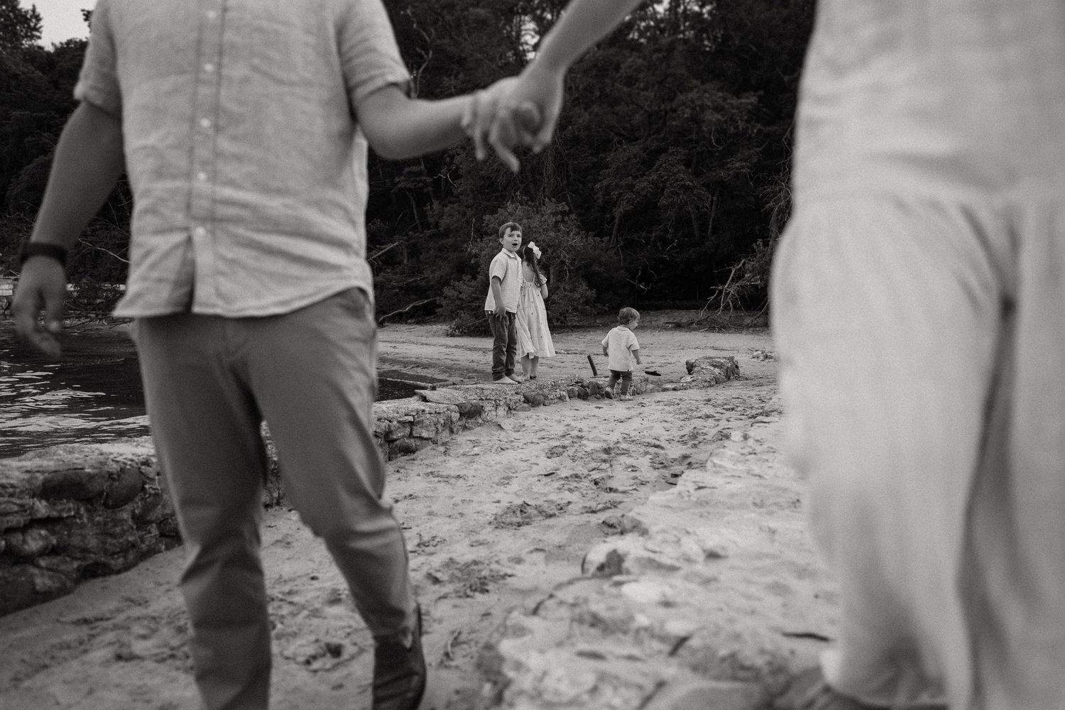 People holding hands walk along a rocky coastal area.