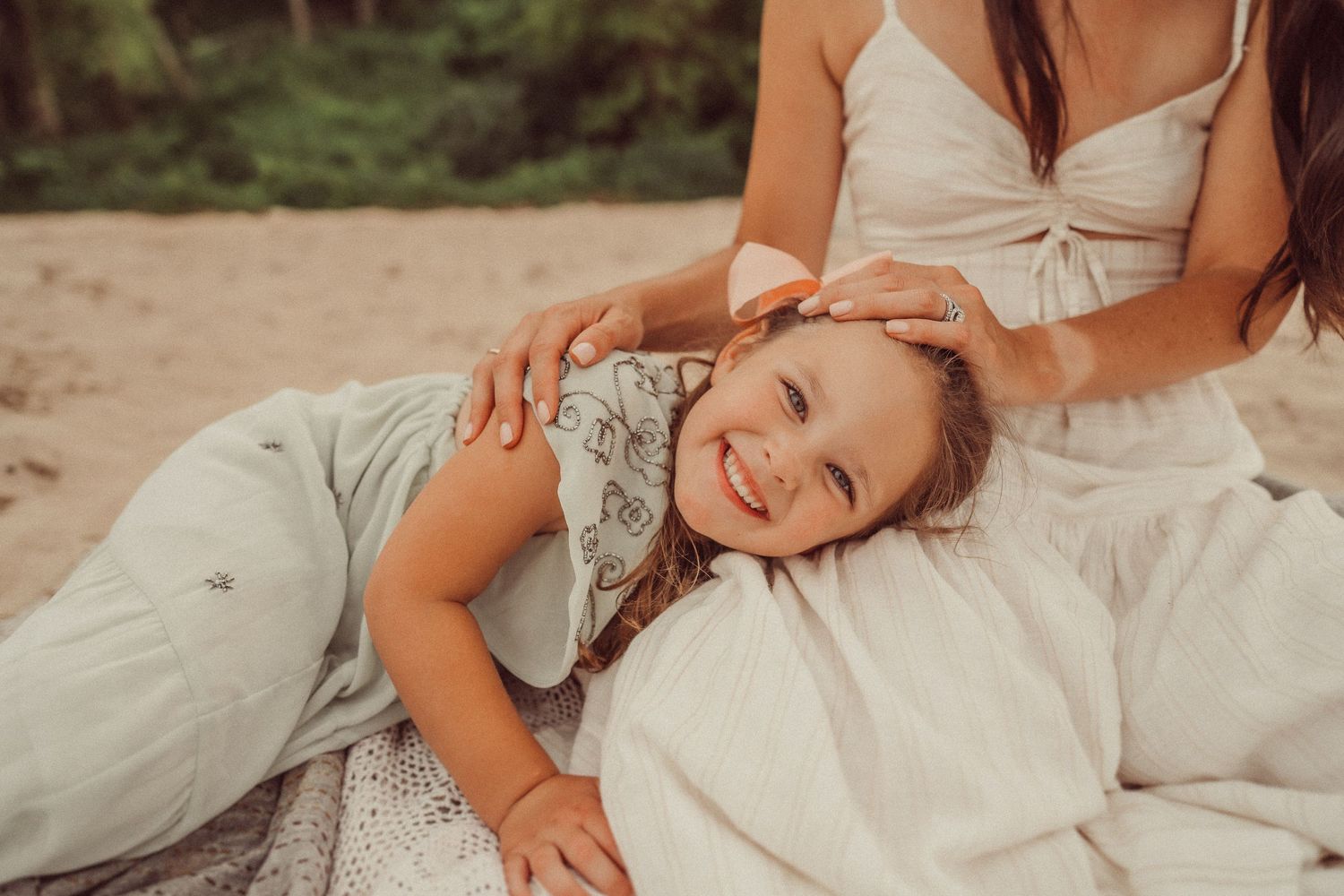 A joyful candid moment between two people relaxing on a white blanket at the beach.