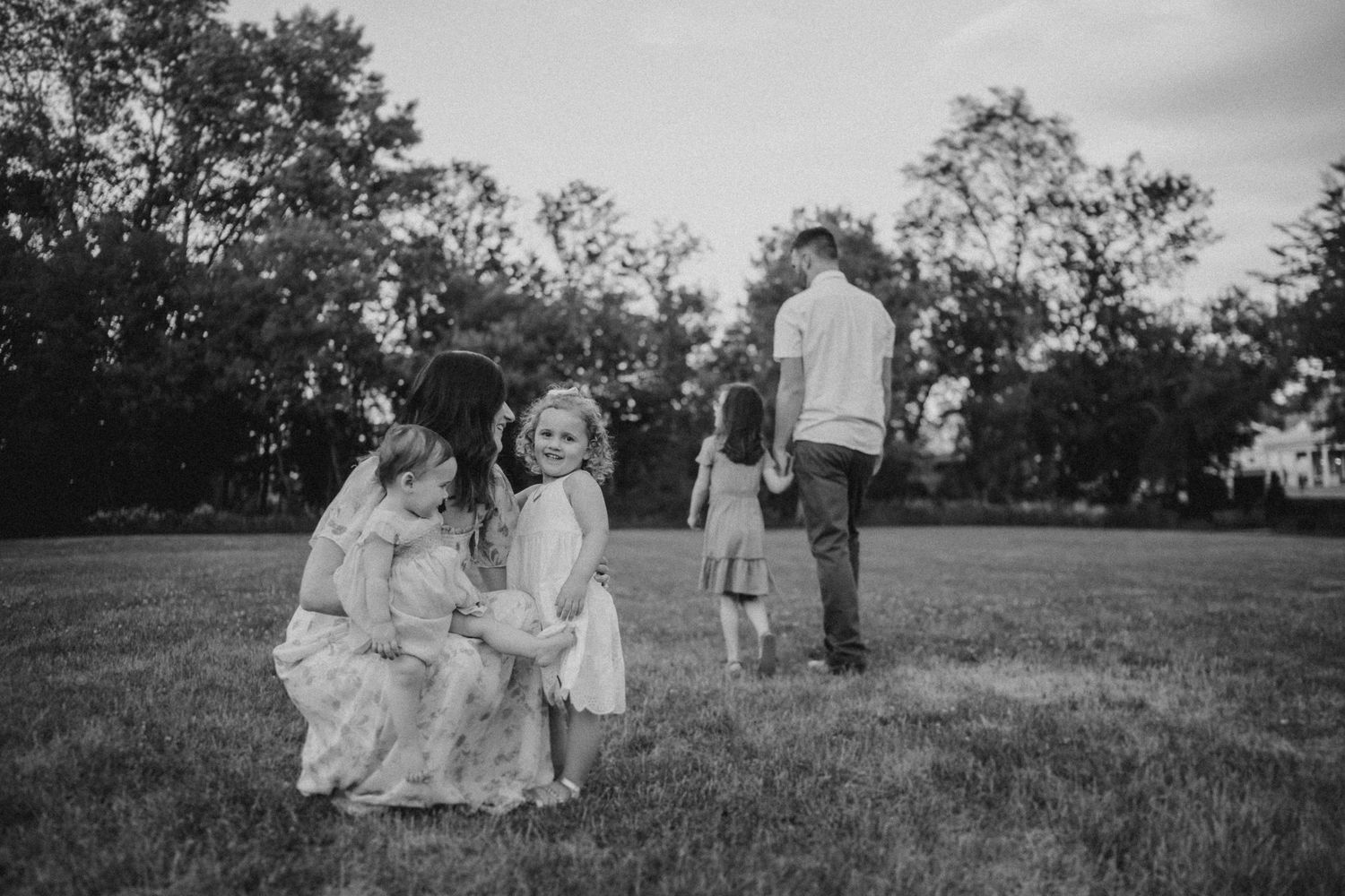 A black and white image of a family sharing tender moments together in an open field.