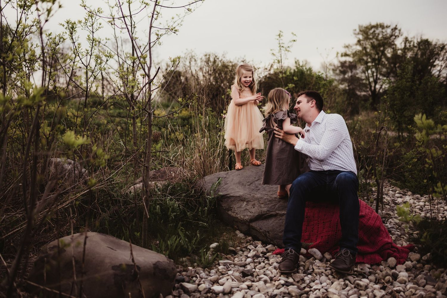 A heartwarming family scene unfolds on a natural rock formation with scattered flower petals.