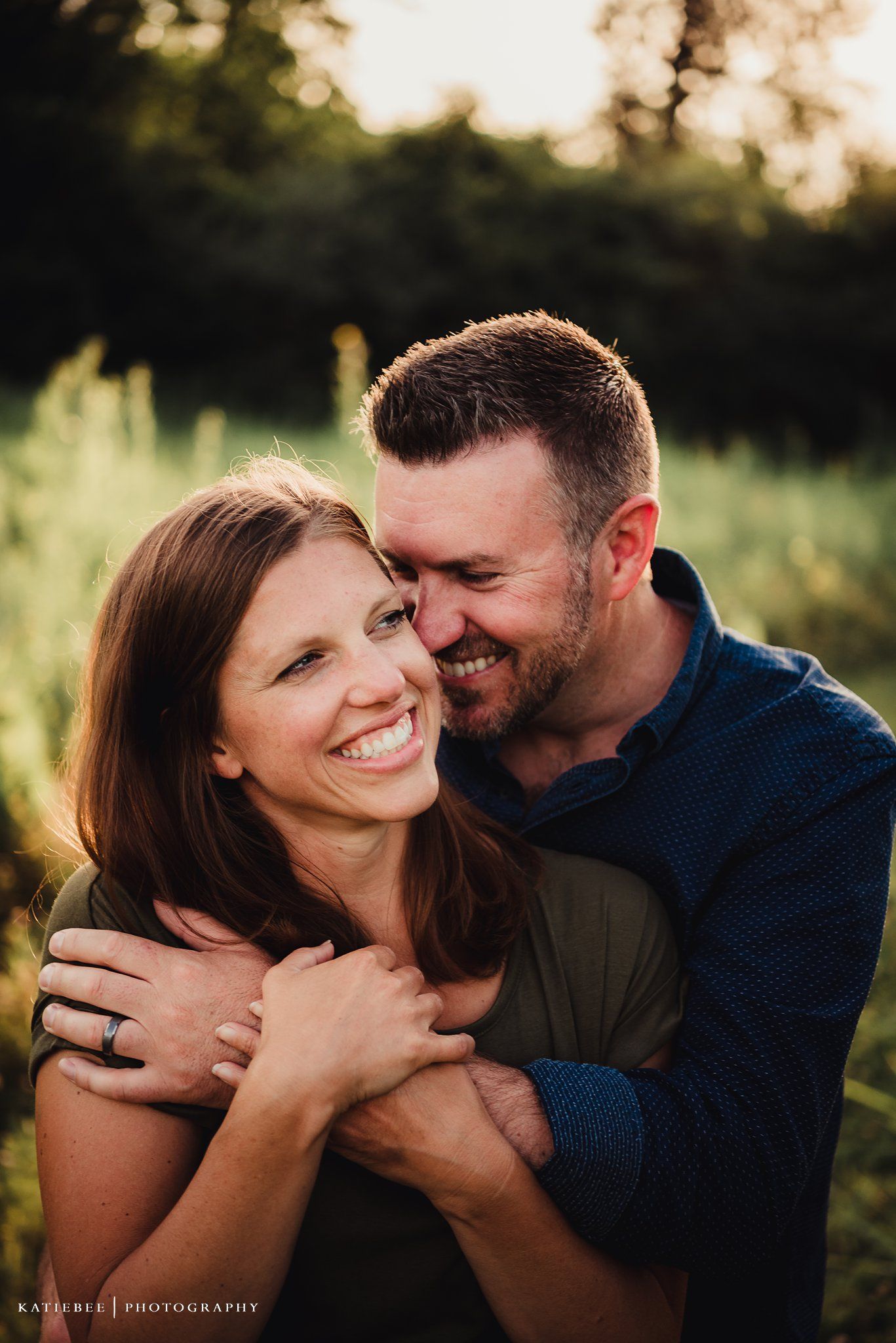 Intimate couple sharing a joyful embrace while laughing together in golden evening light.