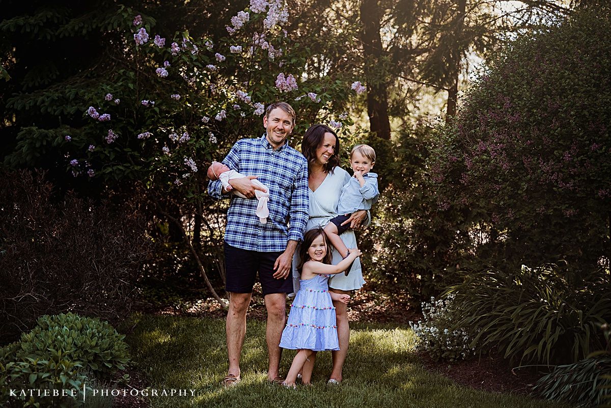 A family poses together outdoors in casual clothing during golden hour.