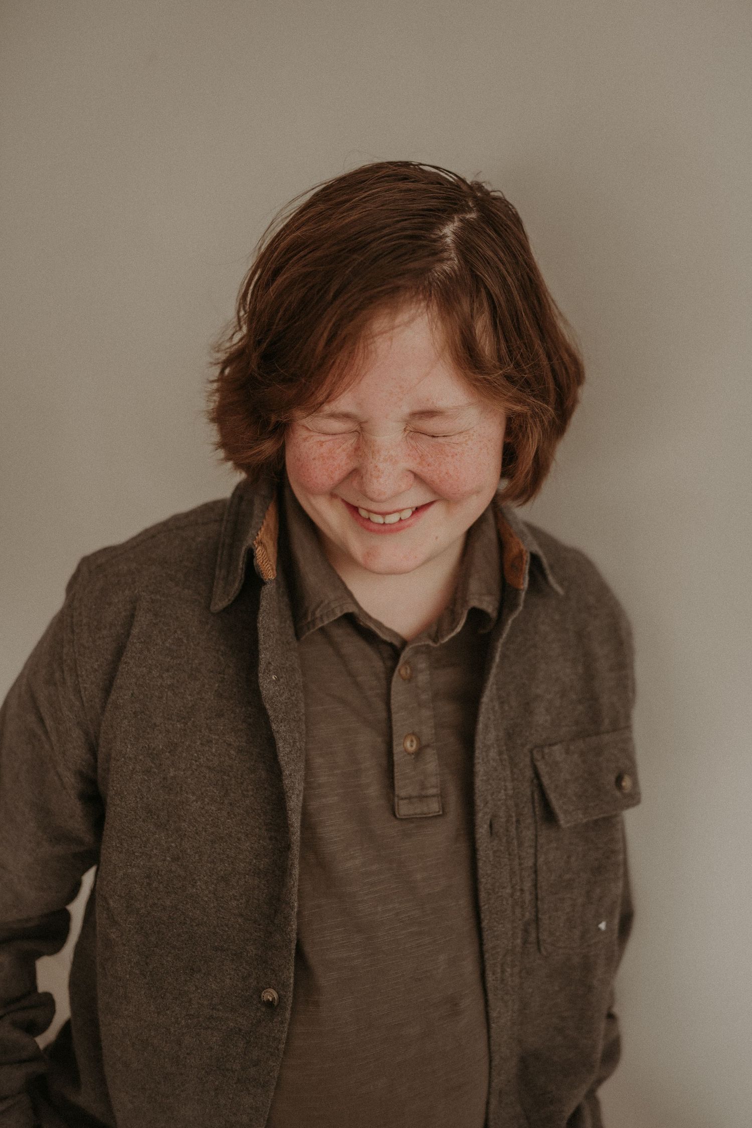 A joyful candid moment captured with closed eyes and genuine laughter in warm lighting.