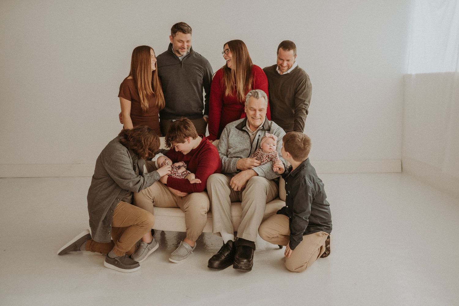 Family group arranged for a professional photo in a minimal white studio space.