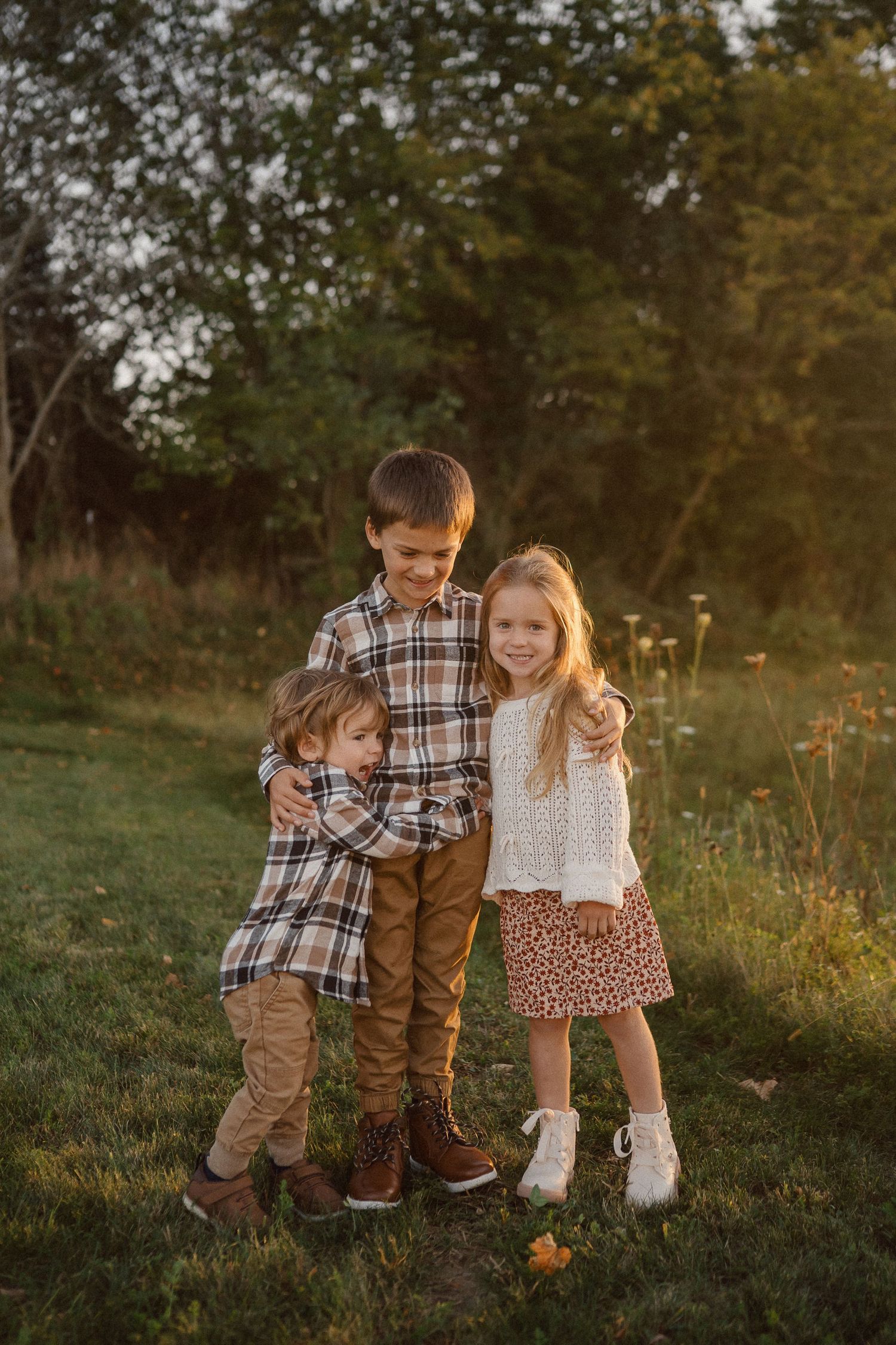 A family plays together in a grassy field during golden hour sunset.
