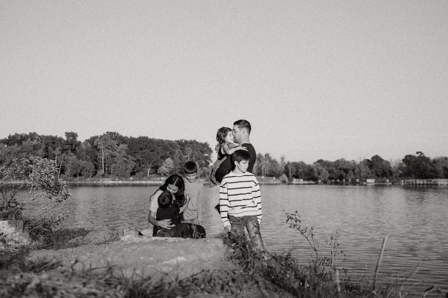 A black and white panoramic collage shows people relaxing by a serene lake on a summer day.
