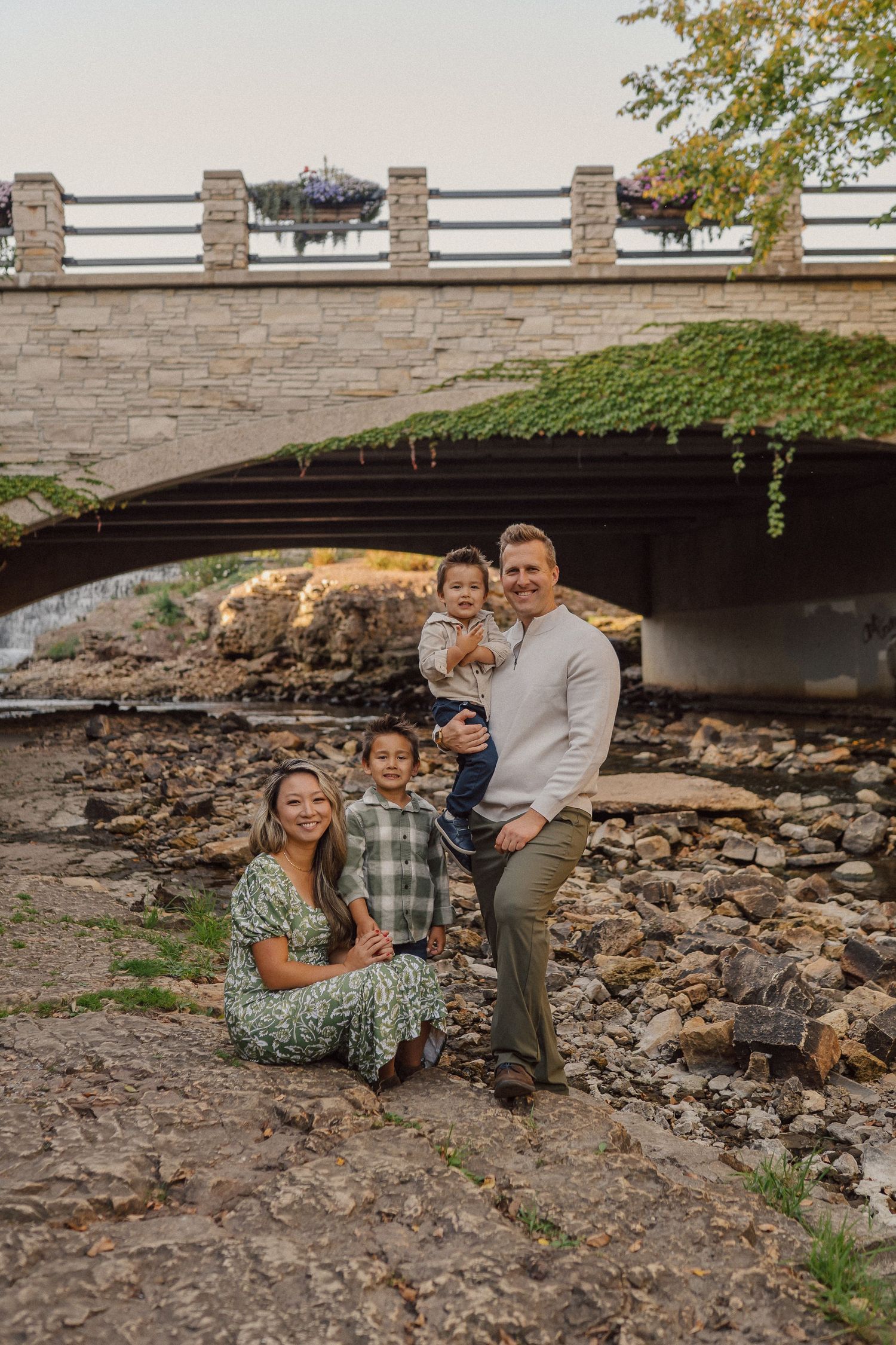 Family lounging together on rocky terrain beneath a stone bridge structure.