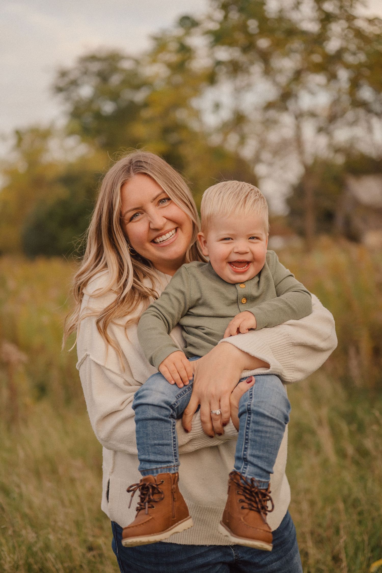 Candid lifestyle photos capture joyful moments between a parent and child in an autumn field.