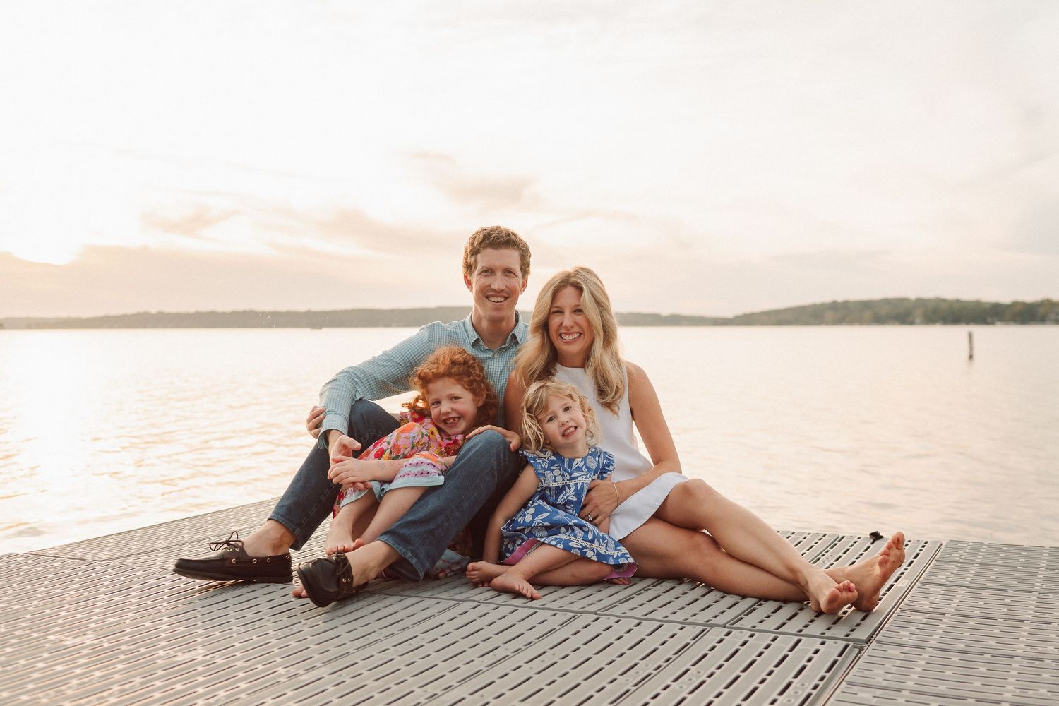 A family relaxes together on a beach boardwalk during sunset creating a warm and intimate moment.