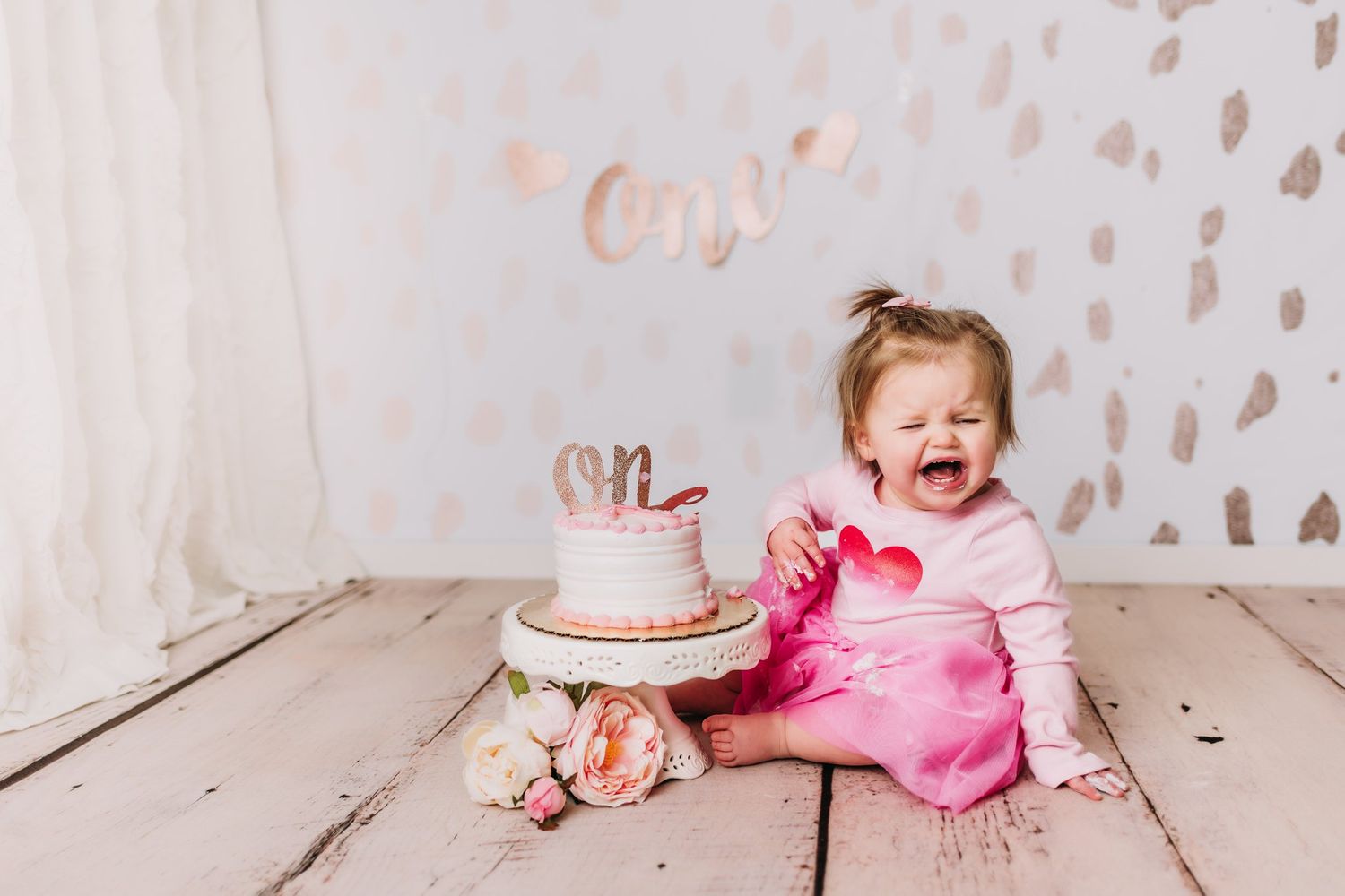 Cheerful moment with pink cake and roses on wooden floor against light patterned wall.