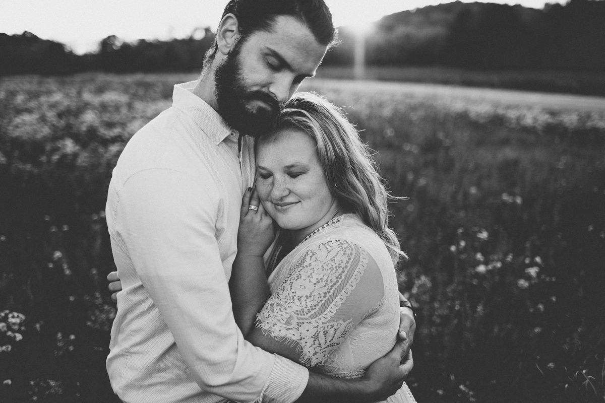 Intimate black and white portrait of a couple embracing in a flowering field.