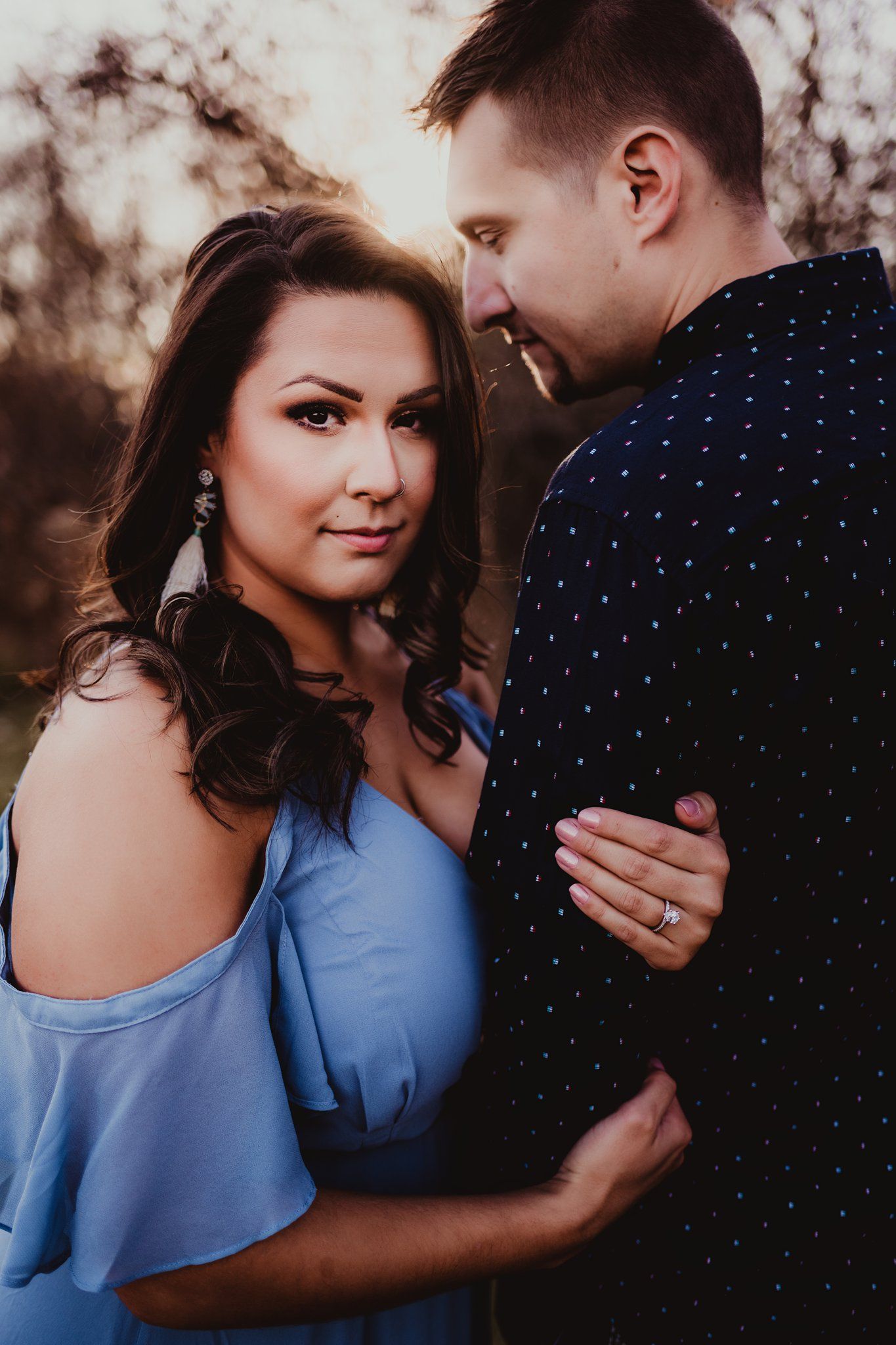 Intimate portrait of couple in autumn field with soft sunset lighting and blue cold-shoulder dress.