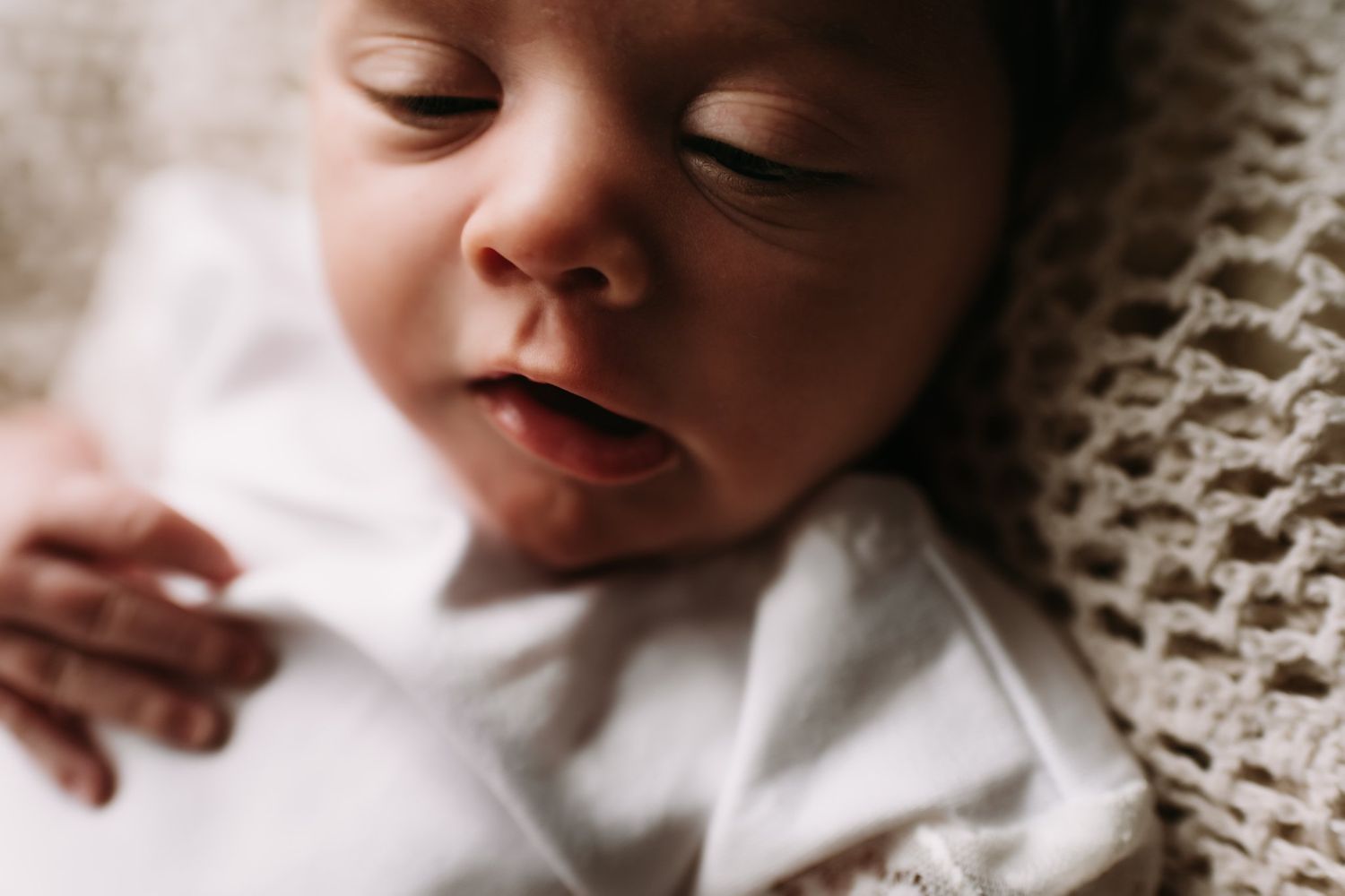 Close-up portrait of sleeping baby against soft knitted blanket texture.