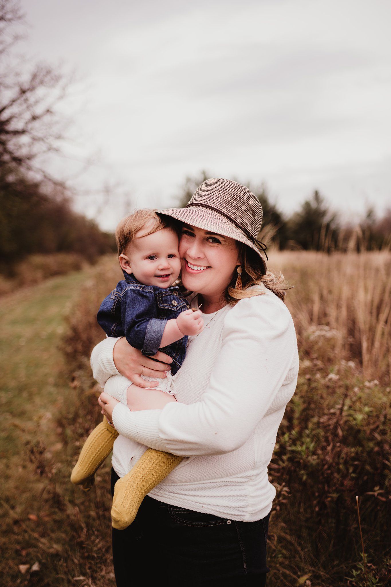 A tender moment between two people against a backdrop of autumn fields and cloudy skies.