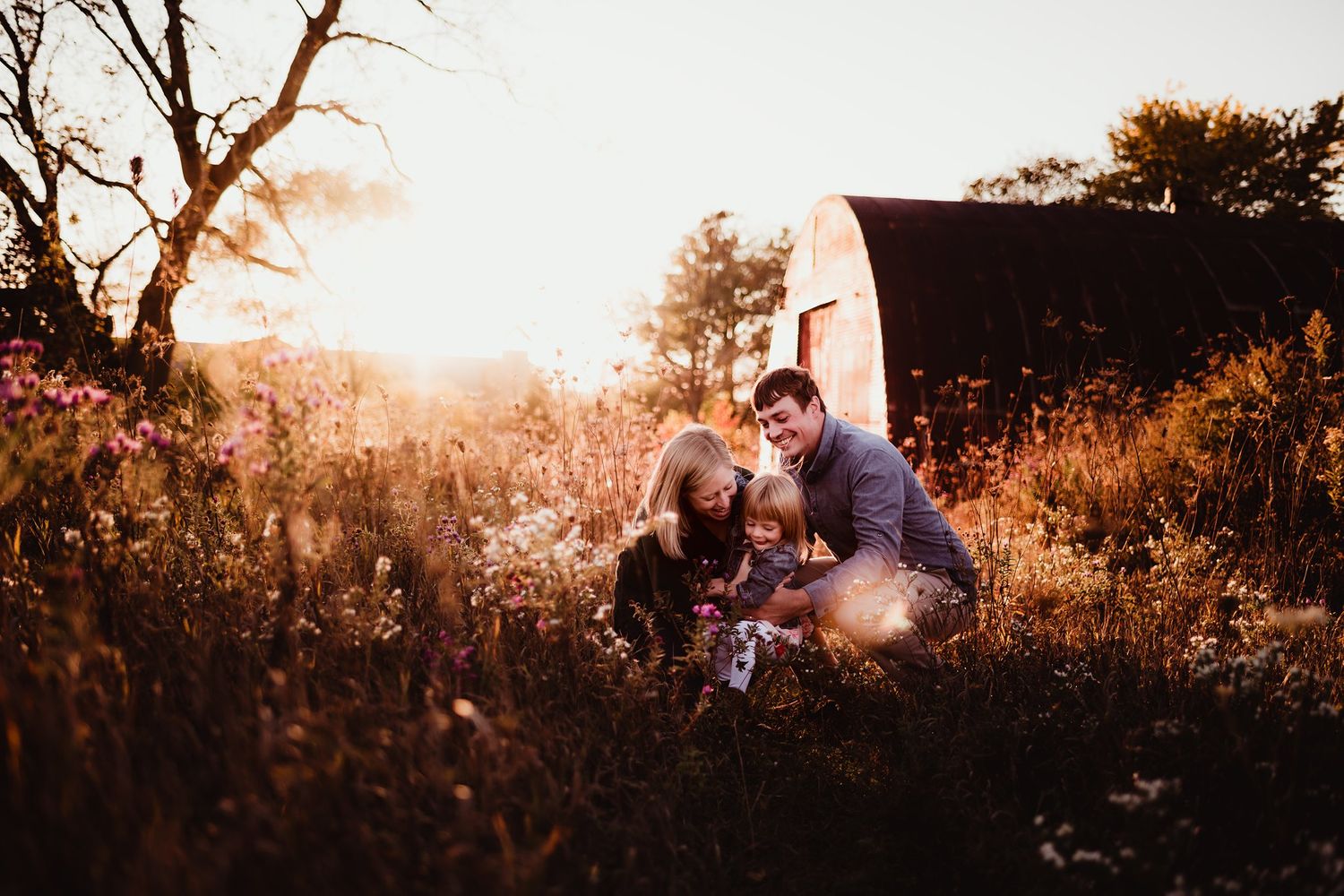 Family portrait session in rustic field setting during golden hour.