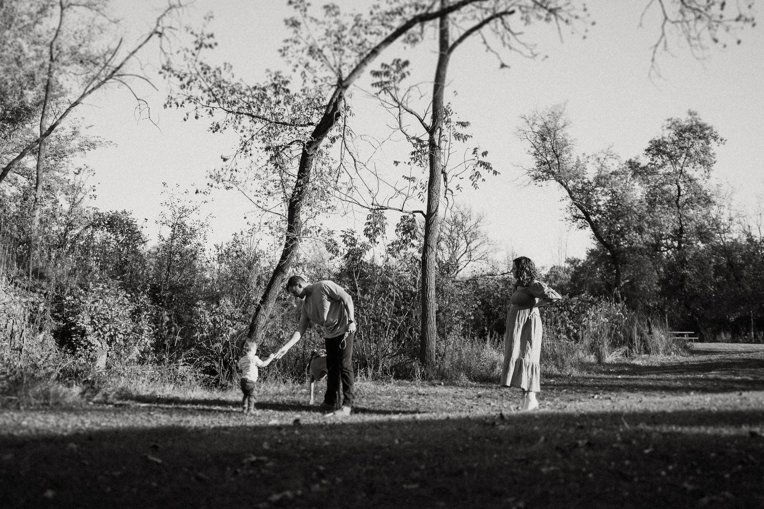 Black and white photograph of family playtime in a natural outdoor setting.