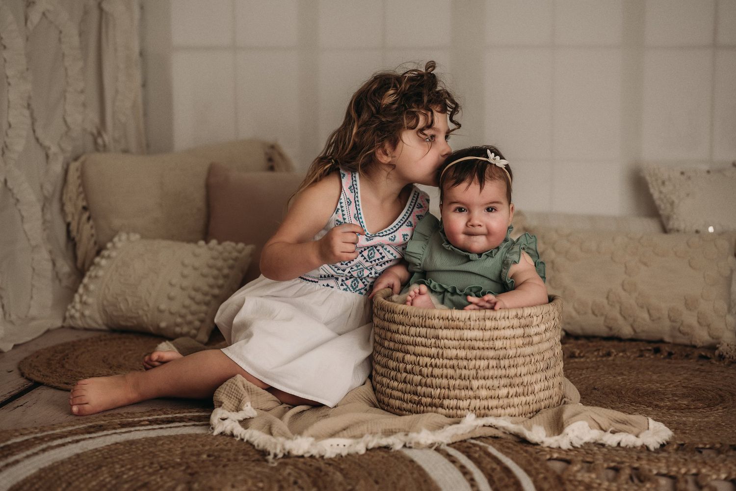 A heartwarming moment between siblings as they pose with a woven basket on a textured floor.