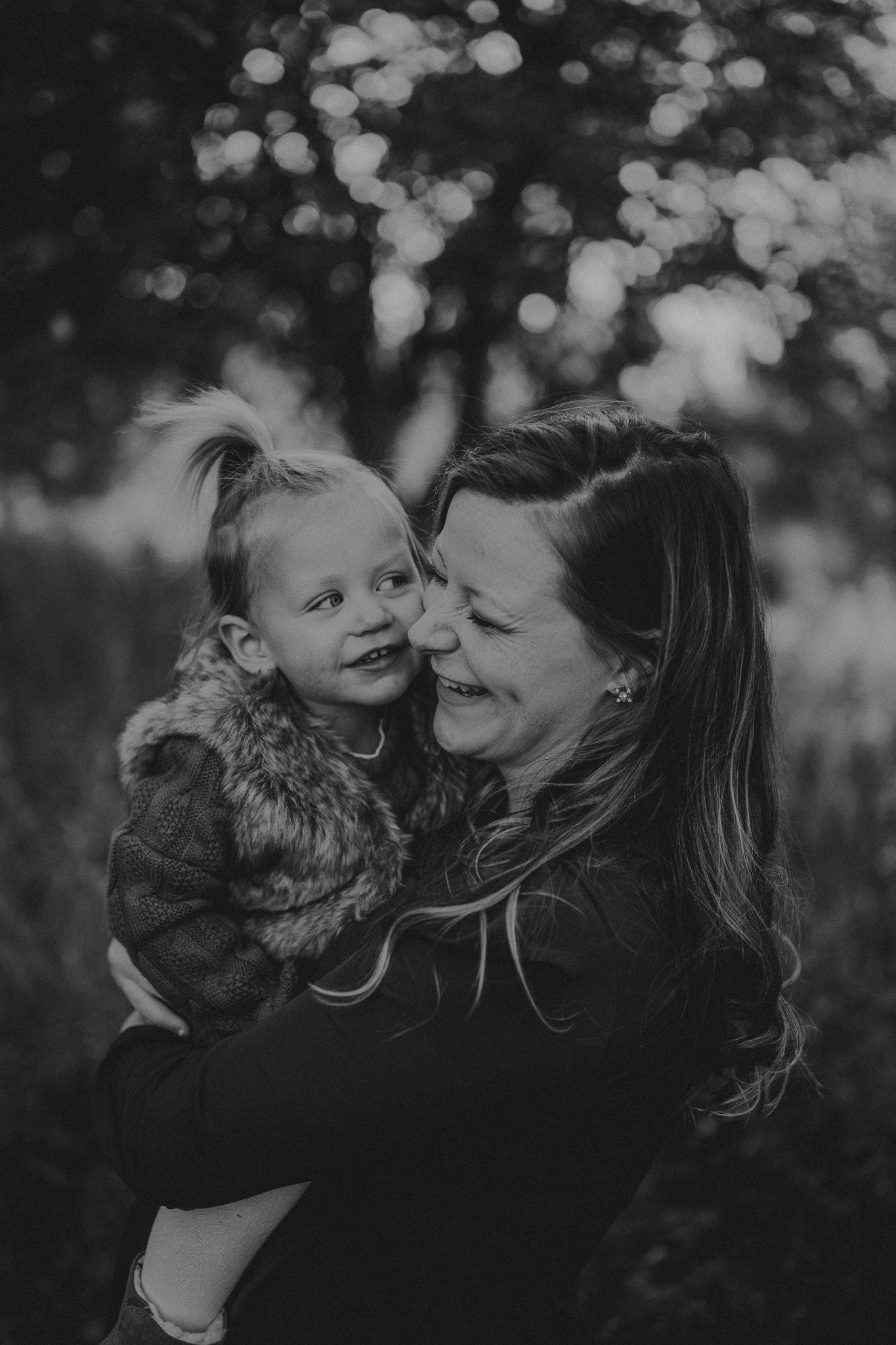 Intimate black and white portrait capturing a joyful moment outdoors with bokeh background.