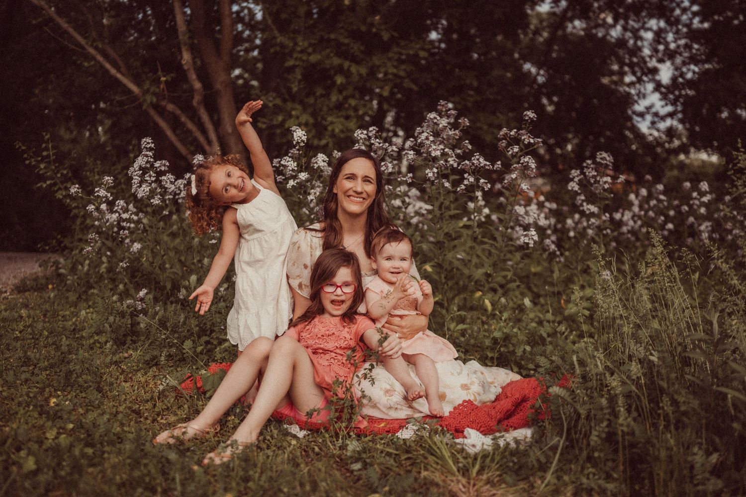 A group relaxes on a red blanket amidst blooming wildflowers on a summer day.