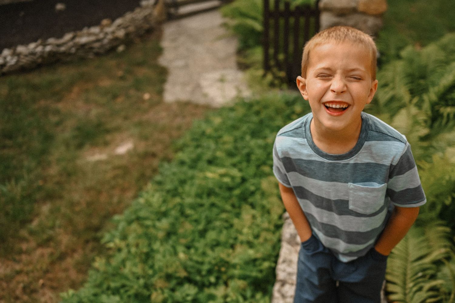 Candid outdoor shot capturing laughter near a stone wall and garden.