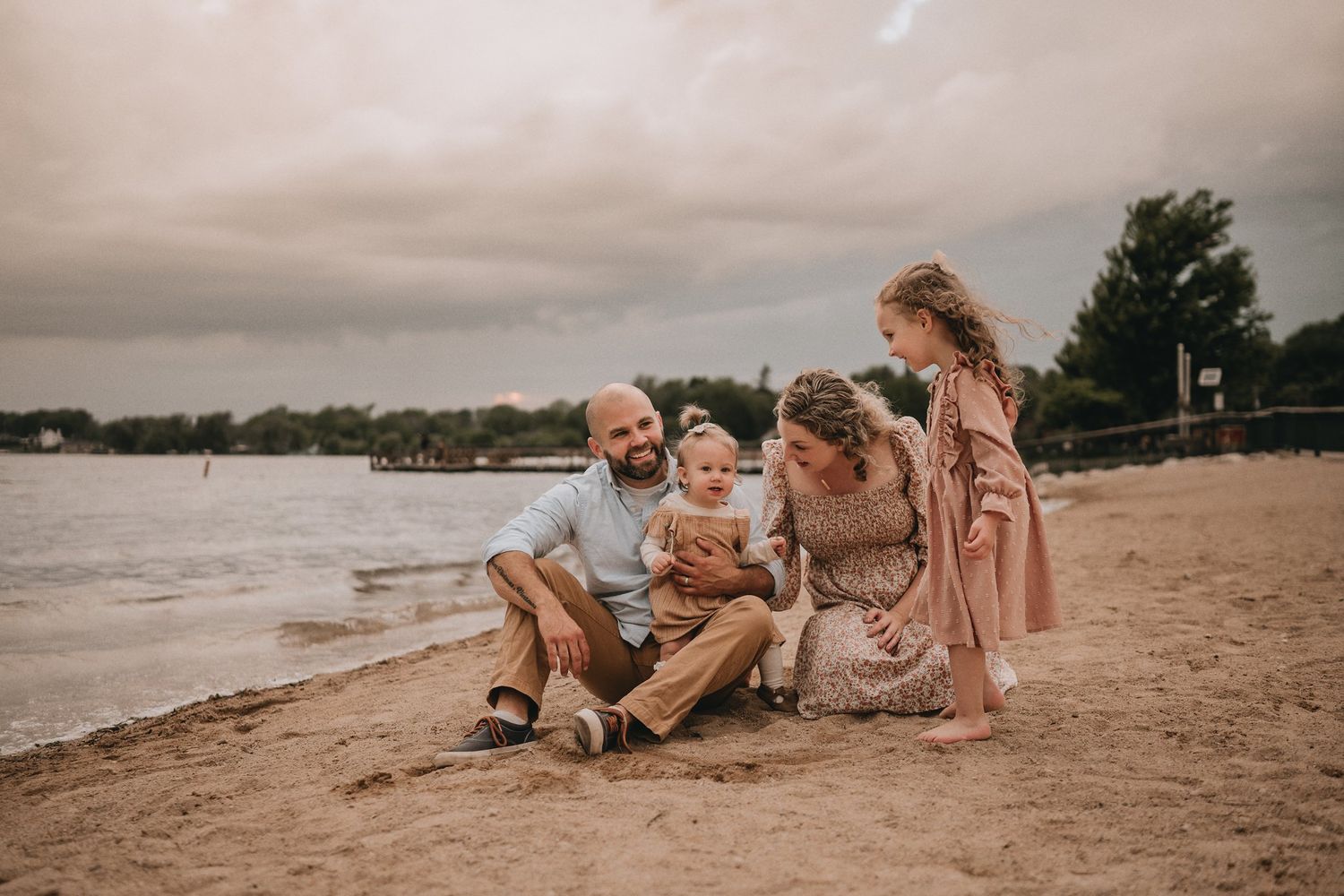 A tender family scene with everyone sitting together on a beach during golden hour.
