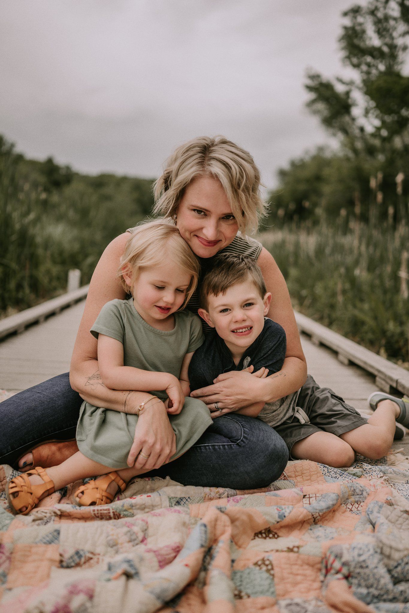 Cozy family moment on a blanket during sunset on a wooden boardwalk.