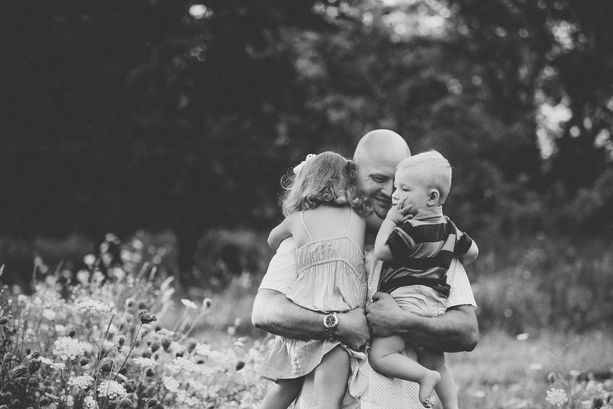 Black and white photo of a tender embrace in a wildflower meadow on a summer day.