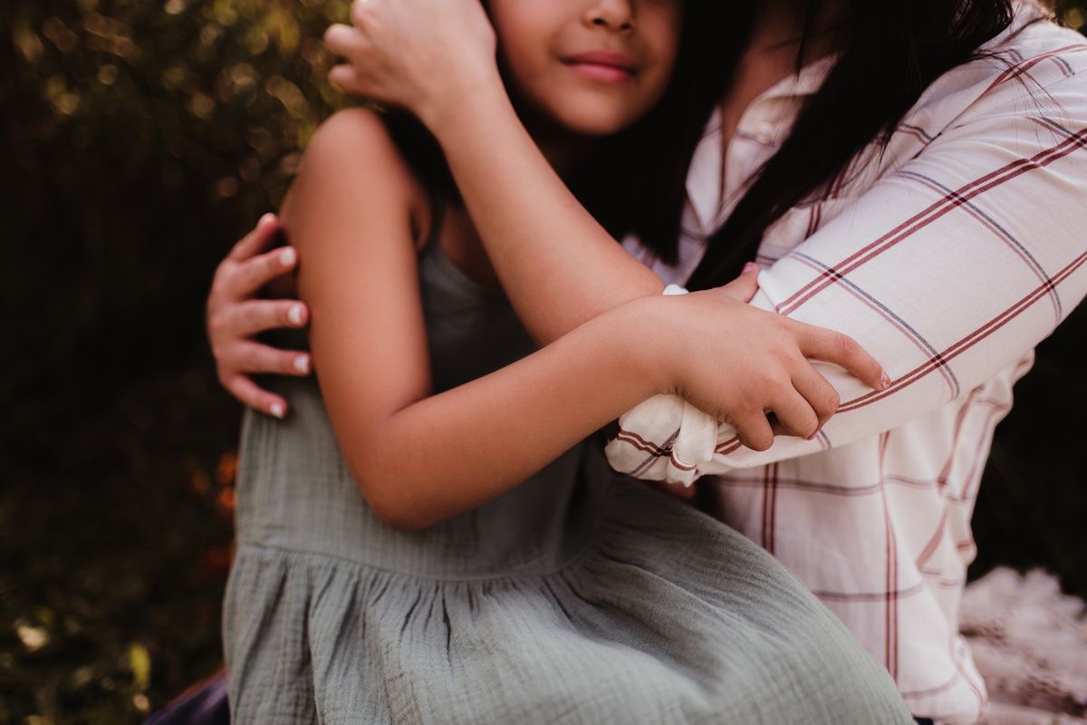 A tender embrace captured in soft lighting between two figures wearing light colored clothing.