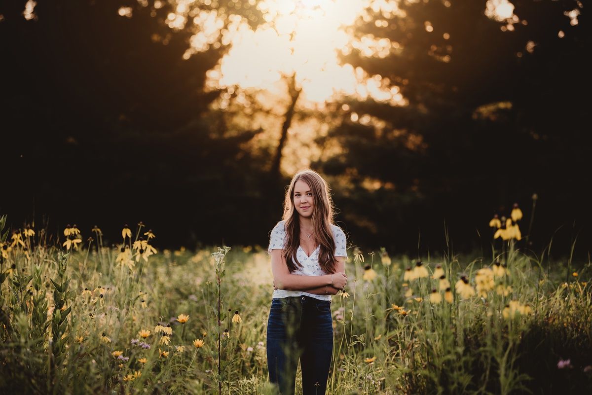Sunset portrait in a wild meadow with golden light filtering through pine trees.