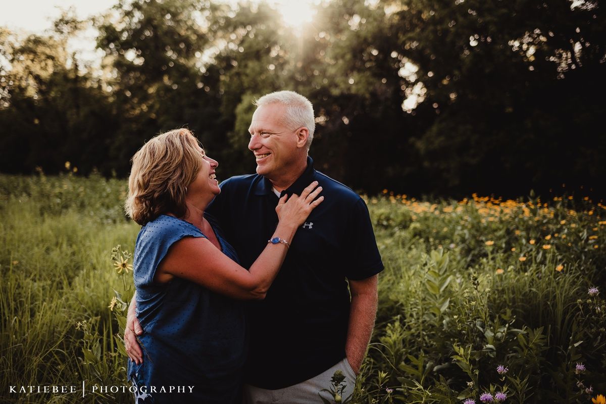 Intimate portrait of a couple embracing in a sunlit meadow with wildflowers.