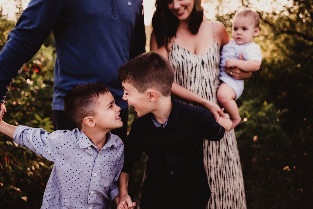 Candid family photo of siblings sharing playful moment outdoors at sunset.