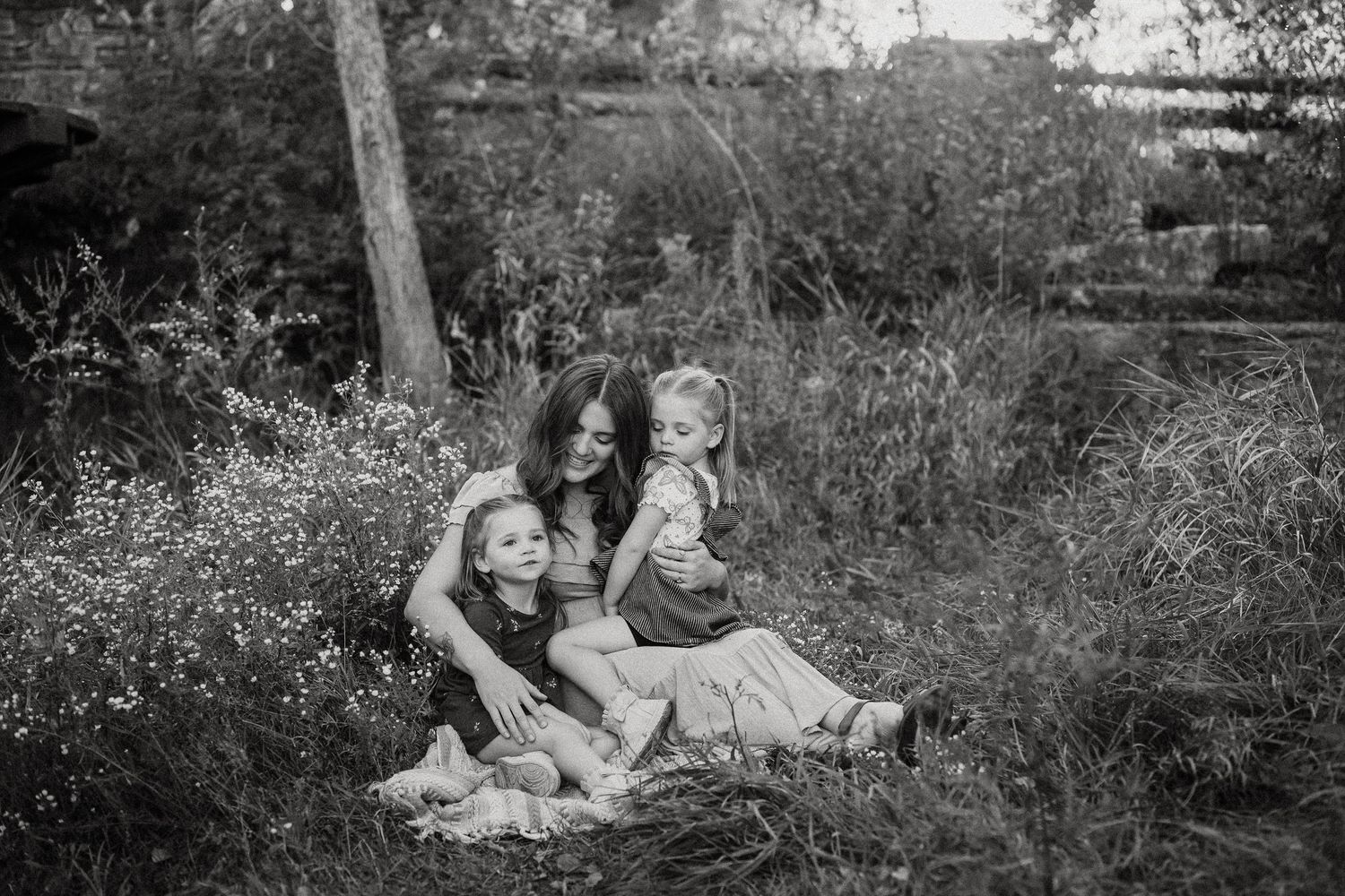 Family relaxing together on grass during outdoor photo session in natural setting.
