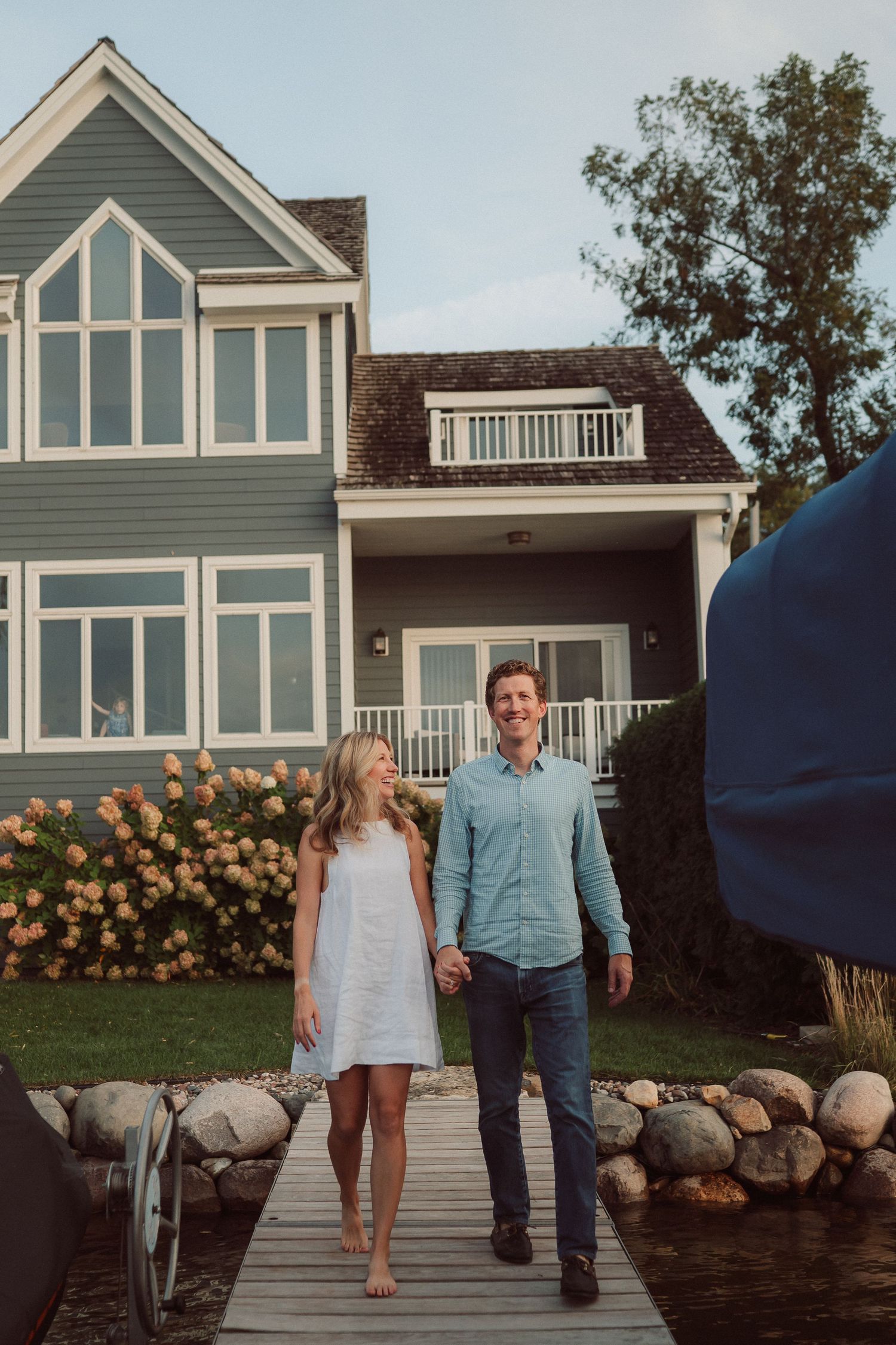 A series of four photos showing a couple walking along a waterfront path with coastal homes in the background.
