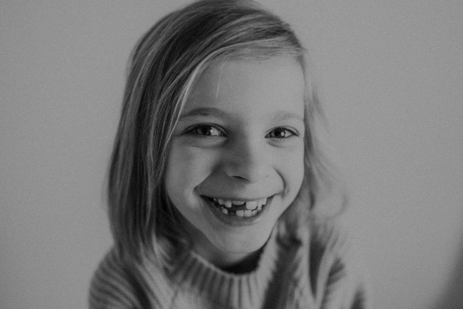 Black and white portrait of a youth in a sweater with a bright expression.