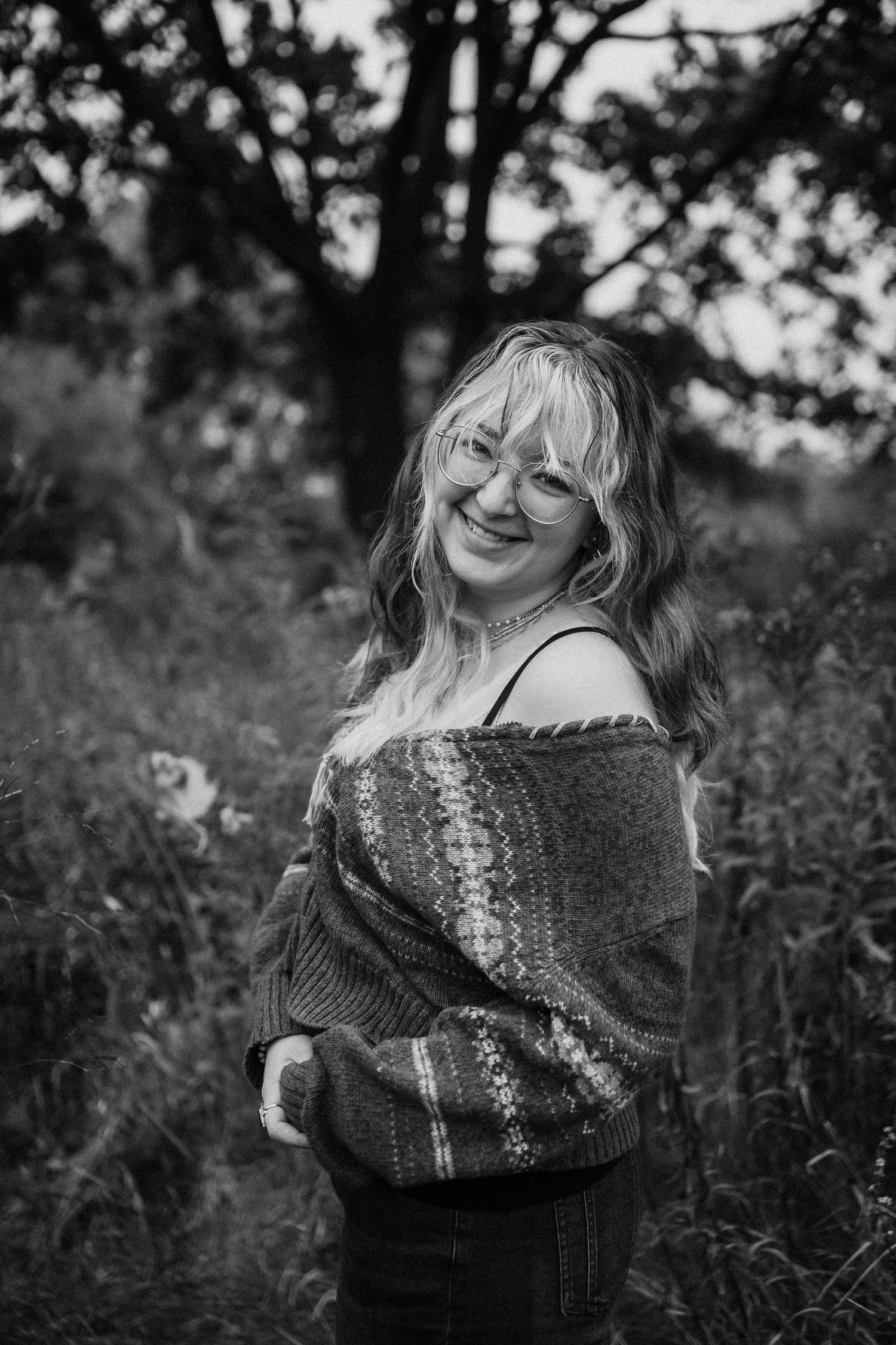 Black and white portrait of person wearing cozy sweater outdoors.