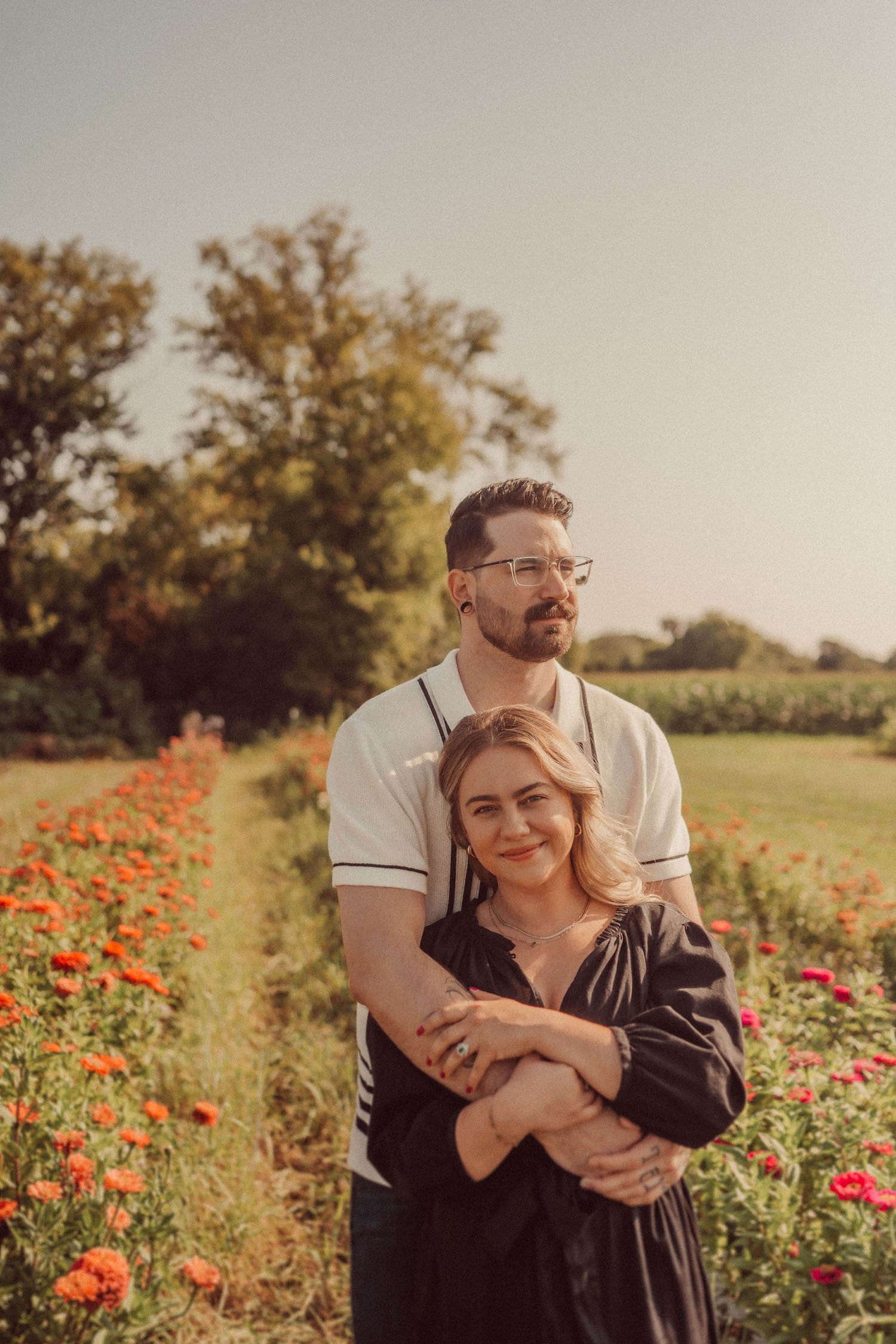 A couple shares an intimate embrace in a field of poppies during sunset.