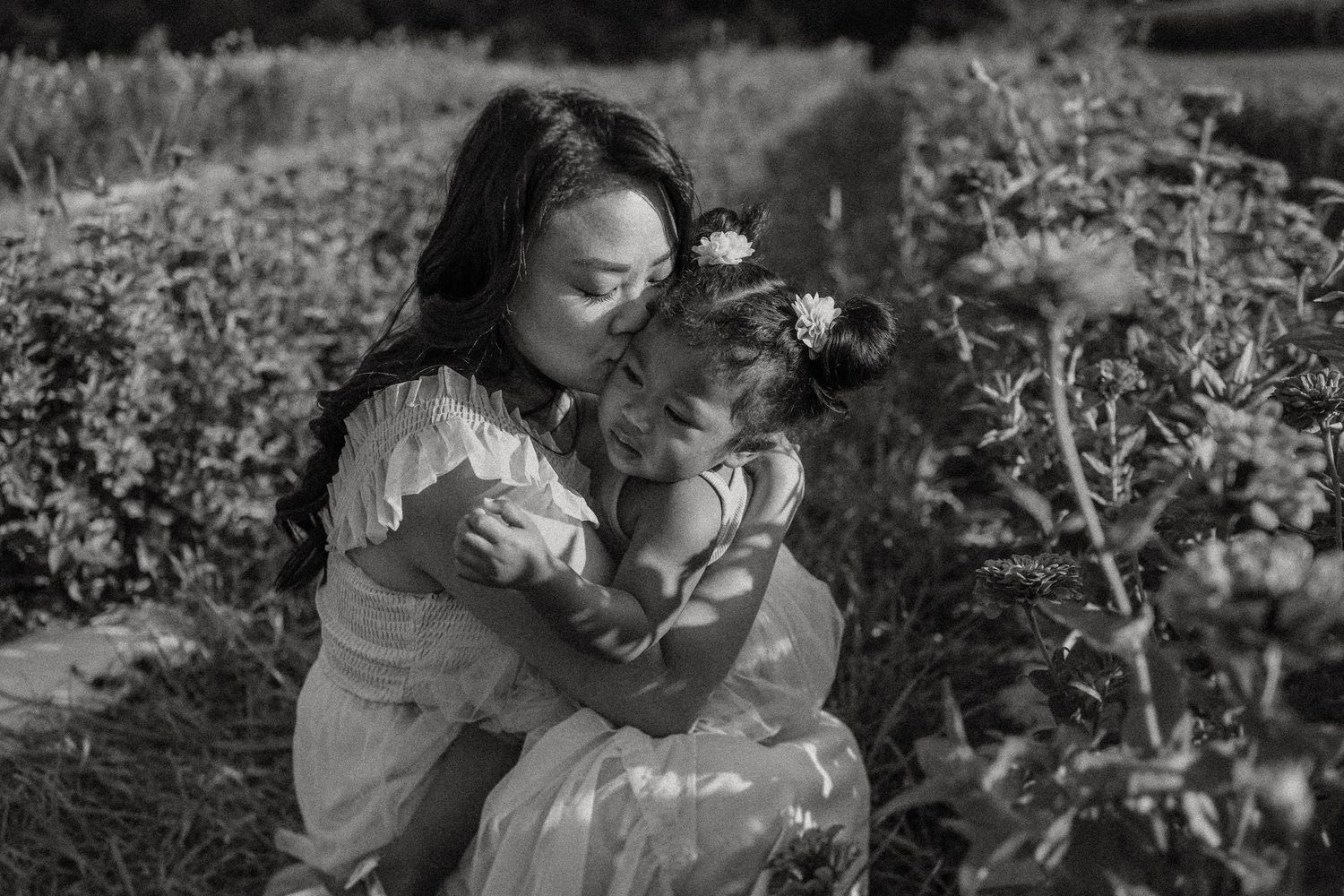Intimate black and white portrait of a gentle embrace among blooming flowers.
