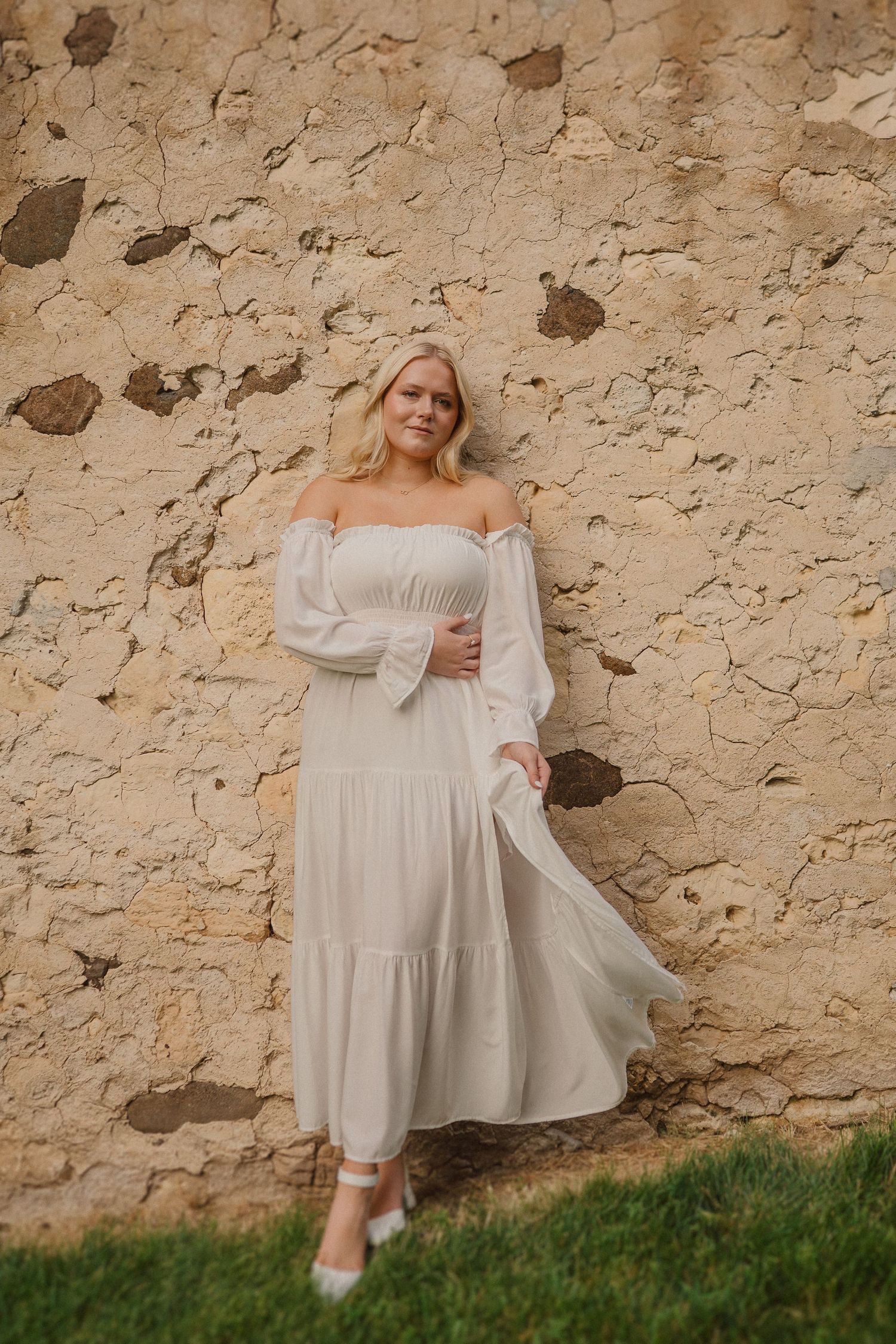 Ethereal white dress captured in a series against rustic stone wall backdrop.