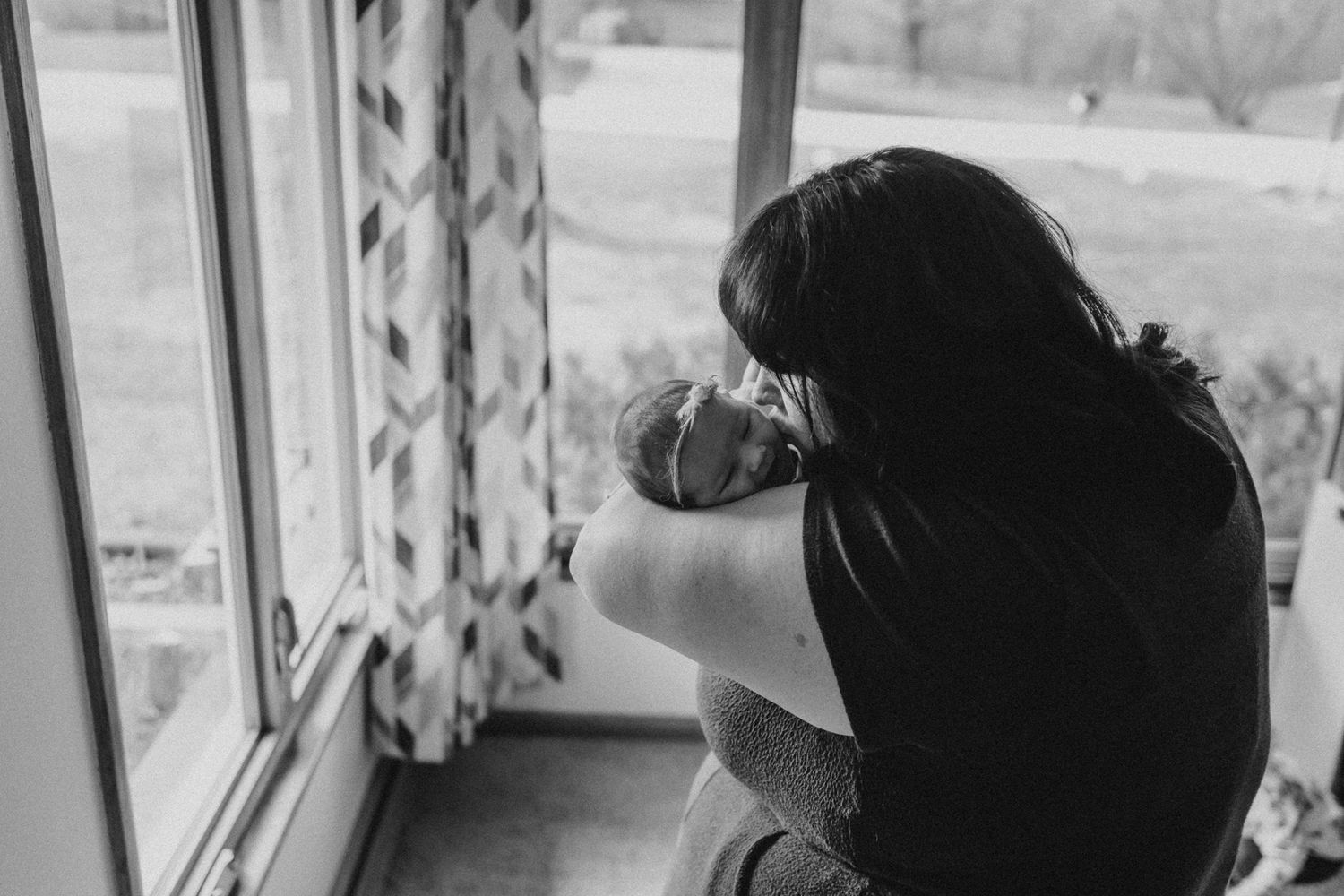Silhouette view of photographer taking pictures by window in black and white.