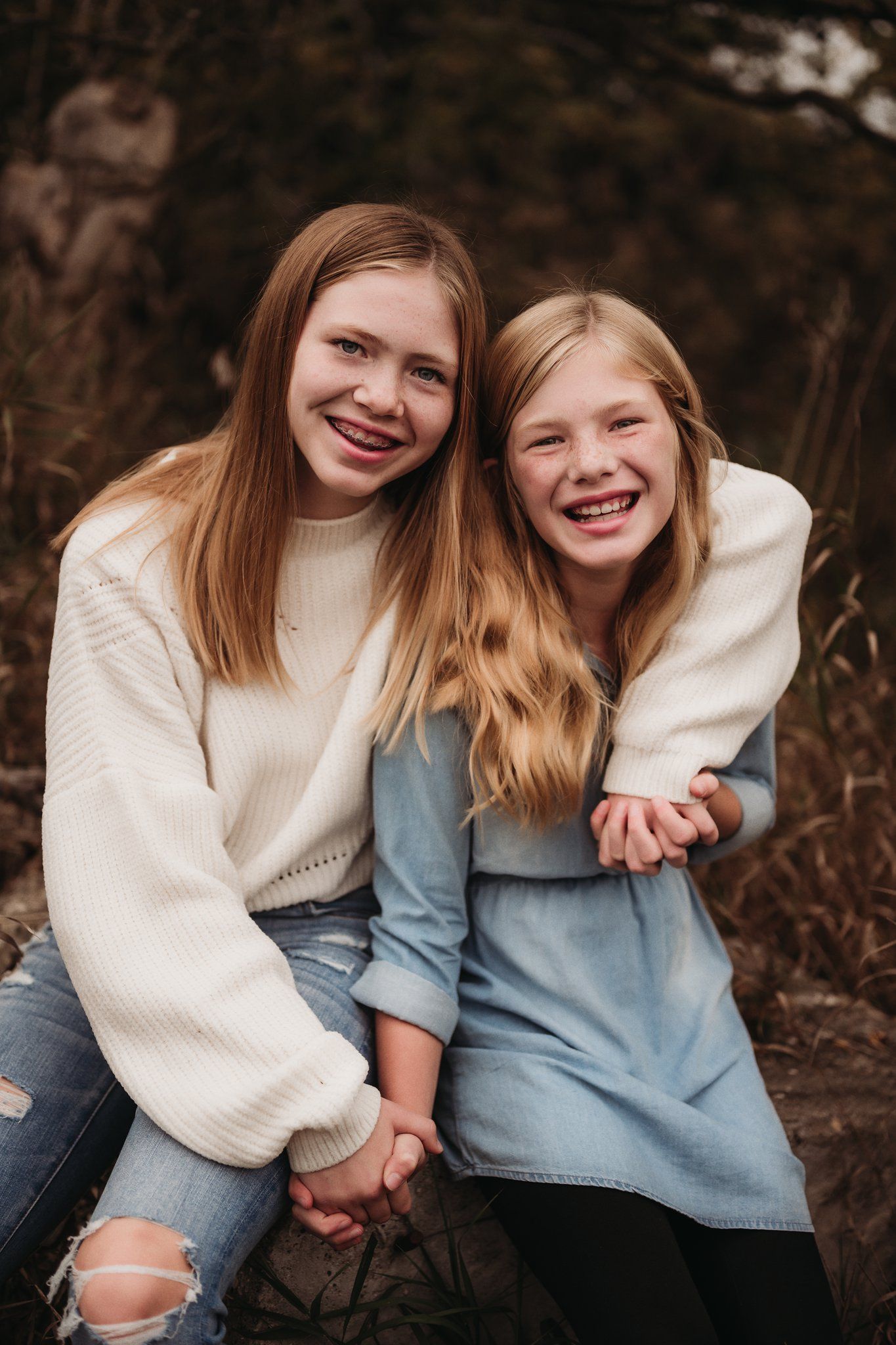 Two young people share genuine laughter while wearing cozy sweaters outdoors.