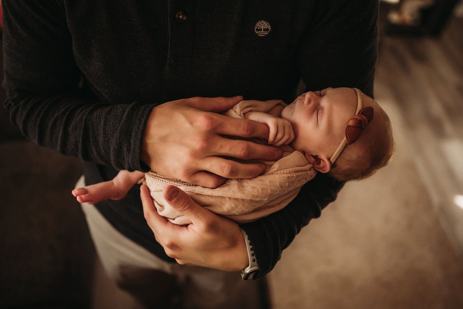 Close-up shot of a sleeping newborn being gently held in caring hands.