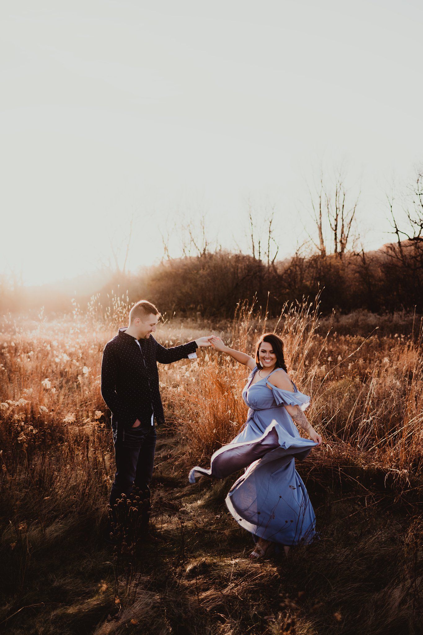 Playful moment captured as blue dress twirls in golden sunset light.