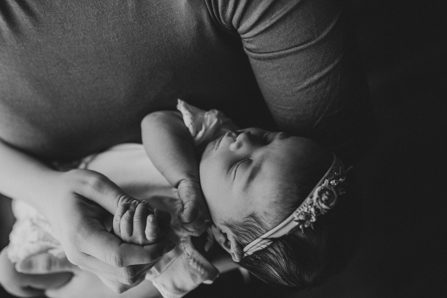 Black and white portrait of a sleeping infant in lace wearing a delicate headband.