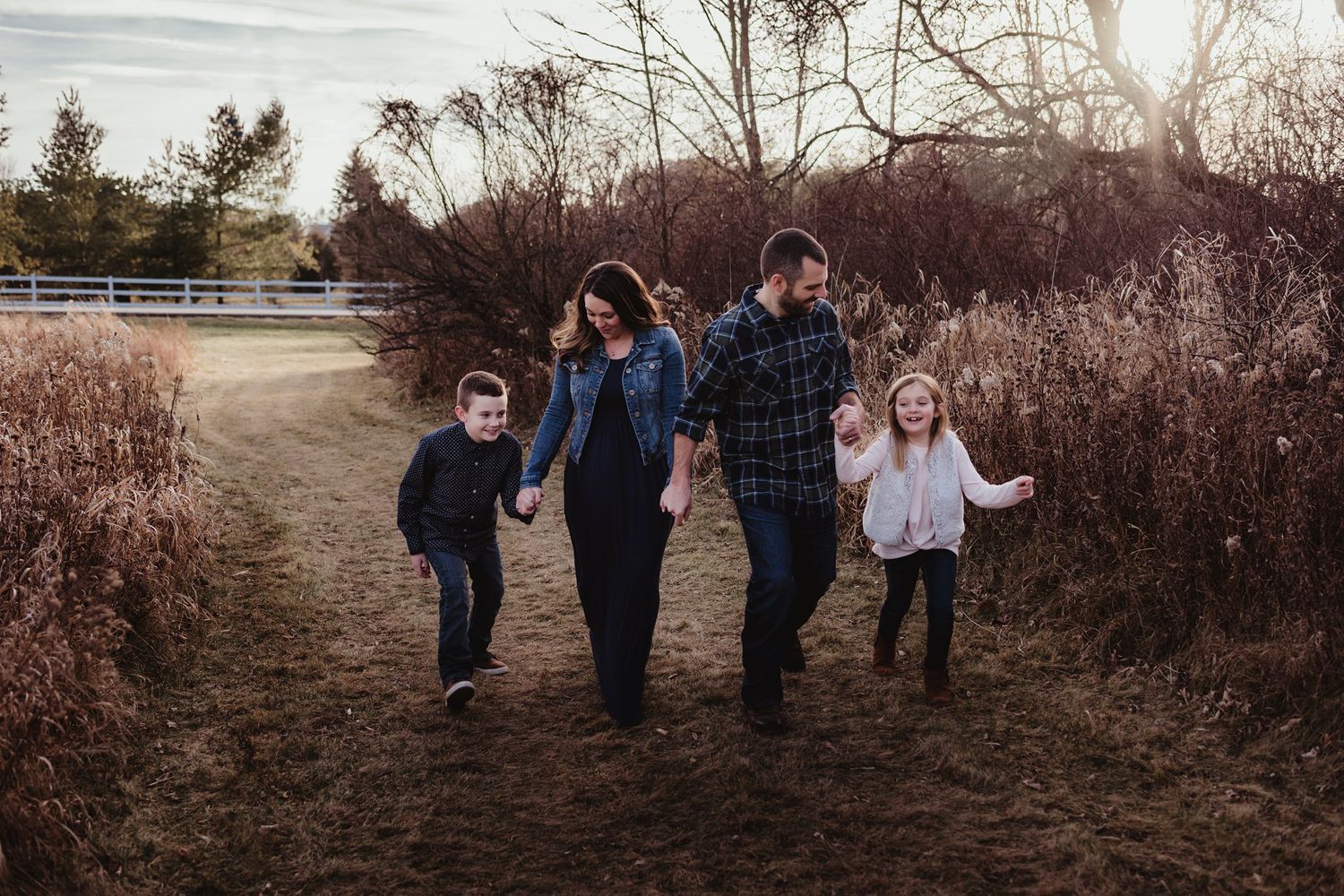 Family of four walking together on dirt path surrounded by brown winter brush.