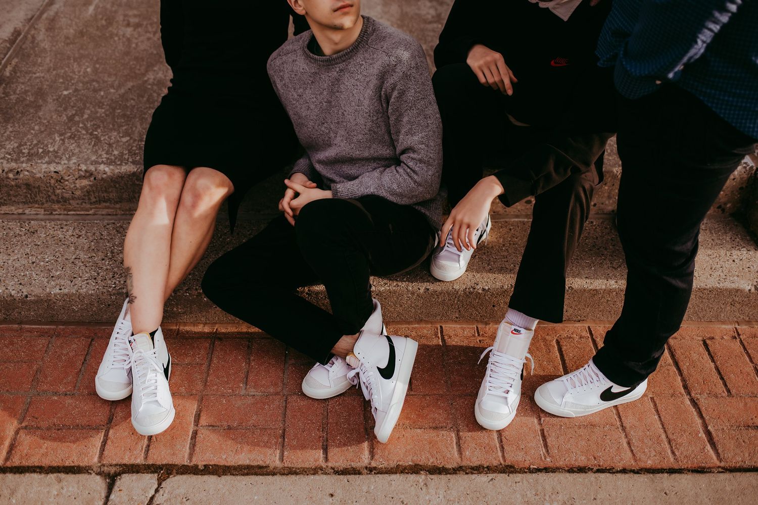 Close-up shot of feet wearing matching white Nike sneakers on brick steps.